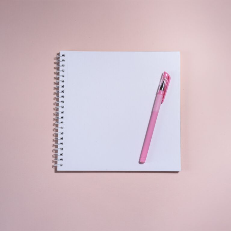 Opened book and pen on it on the pink background.