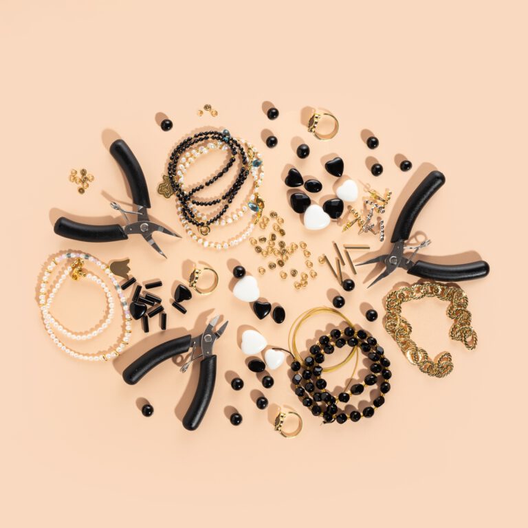 Tools and accessories for DIY jewelry in the workplace. Flat lay on beige background. Creative flat